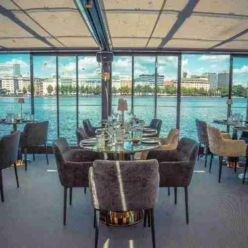 Gedeckte Tische in einem Bootshaus mit Blick auf die Alster