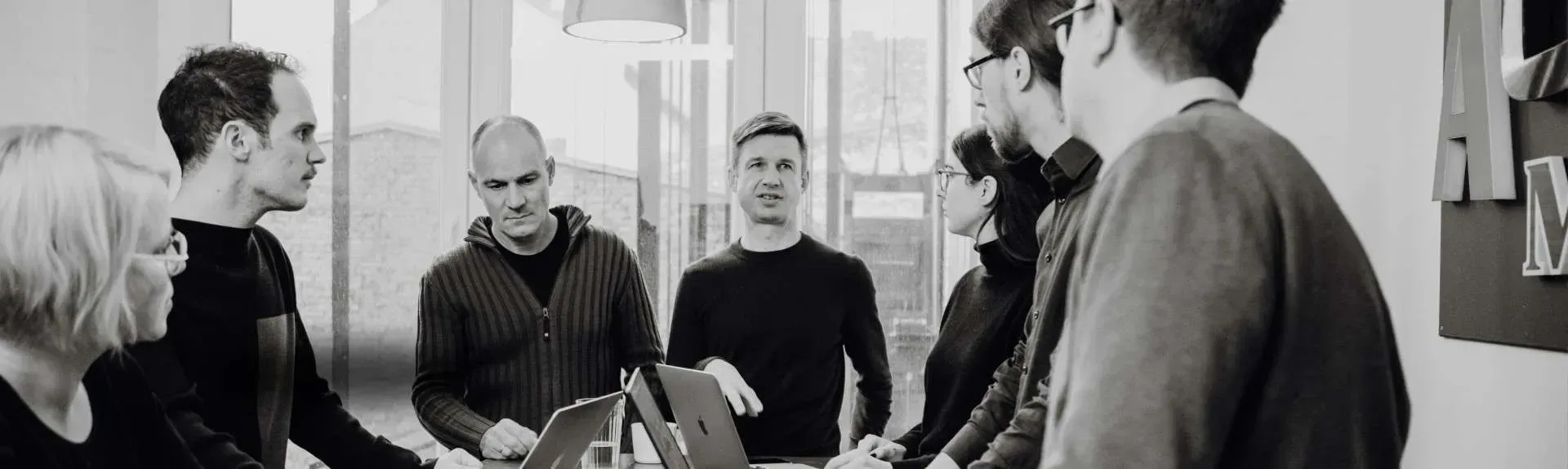 Recording of part of the Effective Donation Team. Everyone is standing around a table with laptops and chatting. 