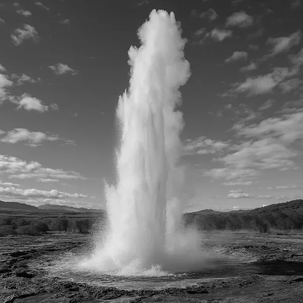 Ein Geysir bricht unter blauem Himmel mit einer hohen Wasserfontäne aus