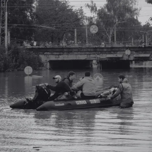 Einsatzkräfte fahren mit einem Schlauchboot durch eine überflutete Straße