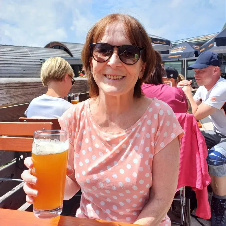 Sabine Sand-Heidinger sitzt lächelnd mit einem Bier in einem Biergarten