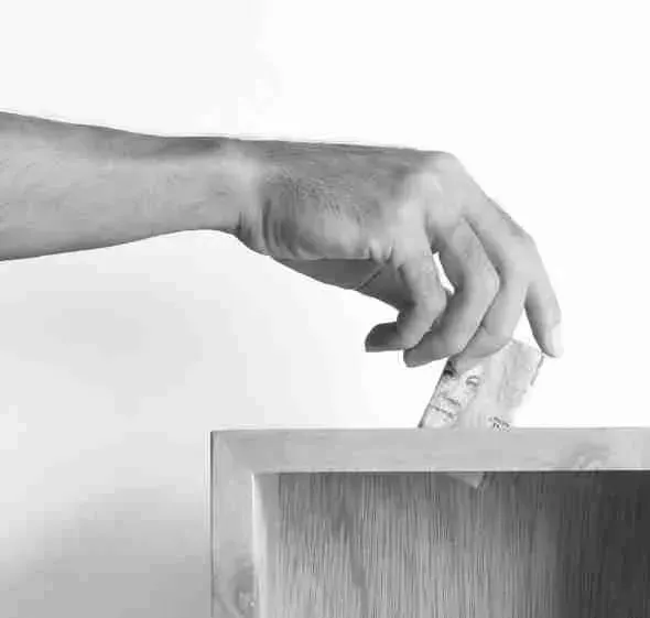 Eine Hand wirft einen Geldschein in eine Spendenbox