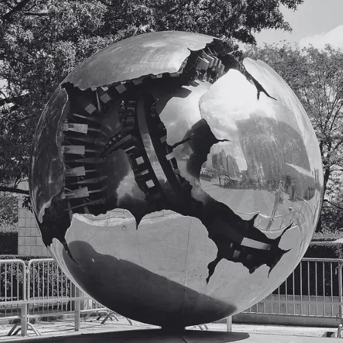Sphere sculpture with a broken outer shell revealing its inner structure outside UN headquarters