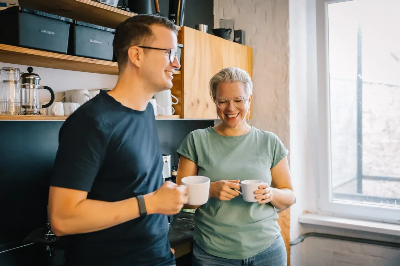 Anne Schulze und Basti Schwiecker mit Kaffeetassen in der Büroküche