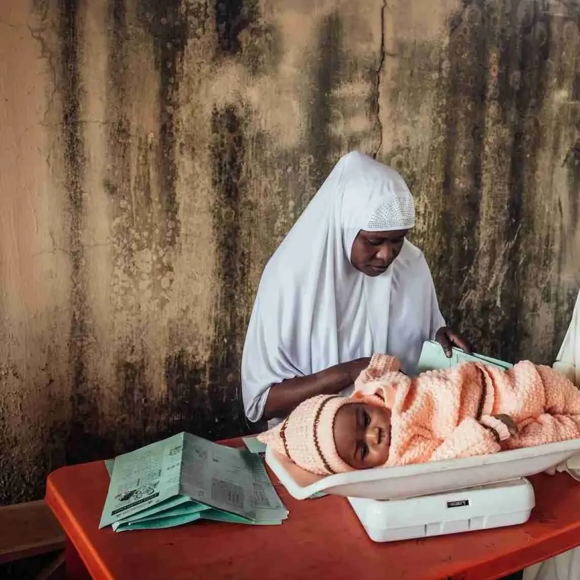 Krankenschwester wiegt ein eingewickeltes Baby auf einer Säuglingswaage