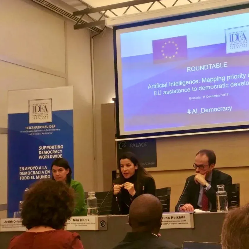 Podiumsdiskussion zu KI und Demokratie mit Bildschirmpräsentation im Hintergrund