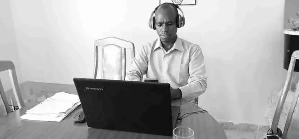 Ein Mitarbeiter von GiveDirectly sitzt an einem Tisch vor einem Laptop mit einem Headset auf. 