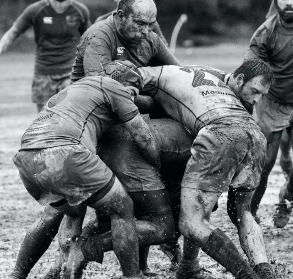 Rugby players wrestle for the ball in a muddy scrum