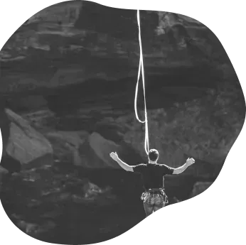 Person hanging on a rope with arms outstretched against a rock face