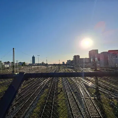 Blick über Bahngleise auf eine Stadtskyline bei Sonnenuntergang